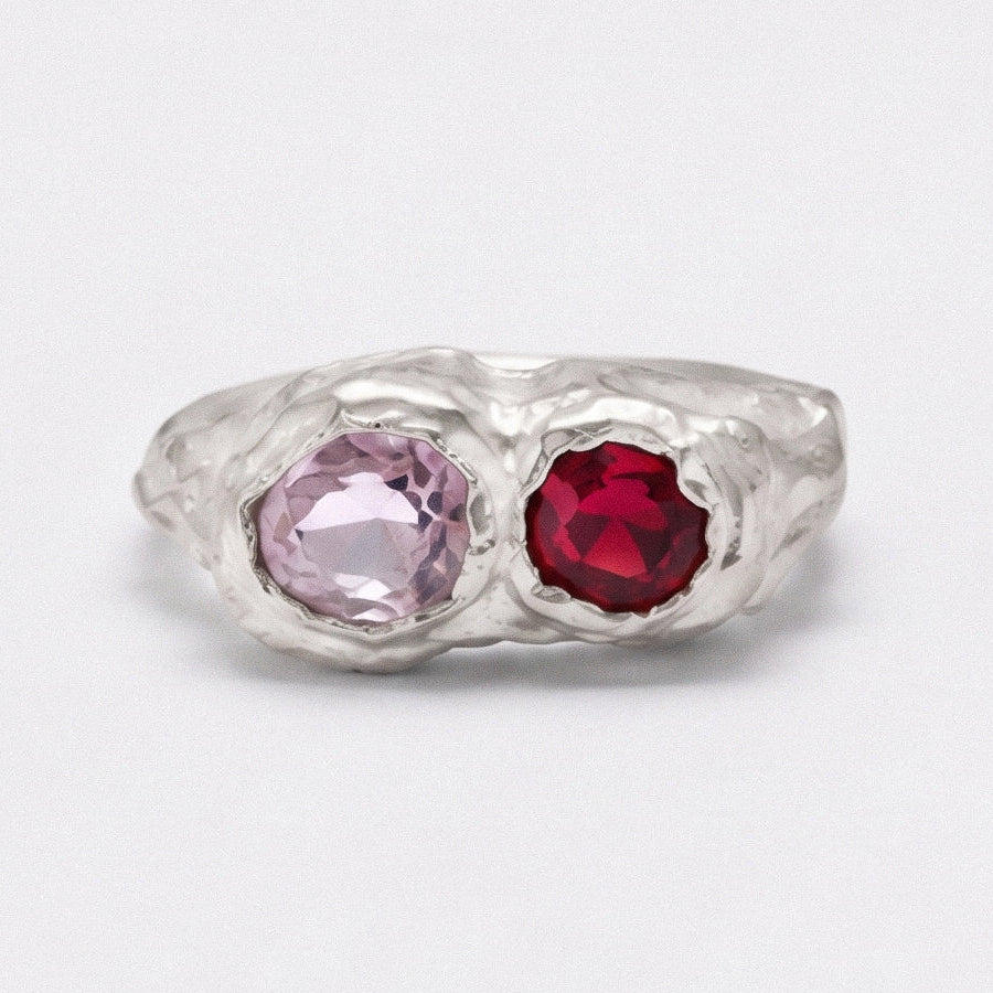 Silver ring with pink and red gemstones on a white background