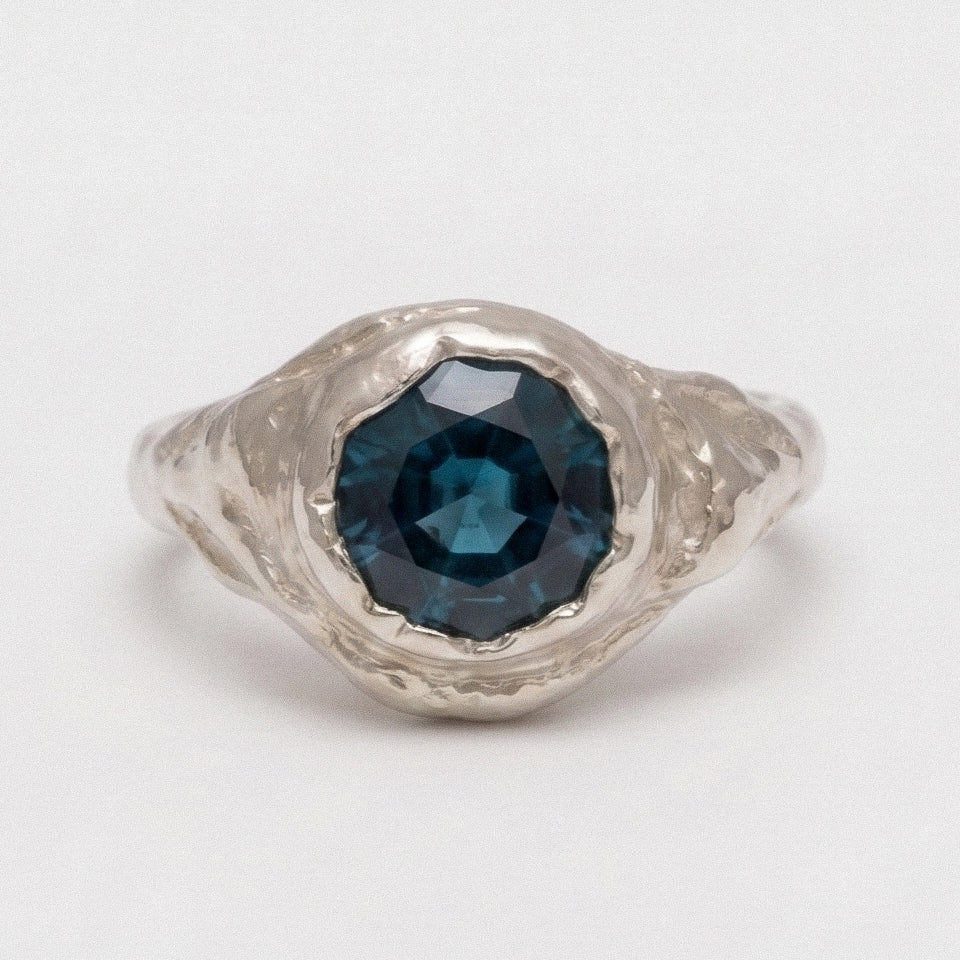 Silver ring with a blue gemstone on a white background