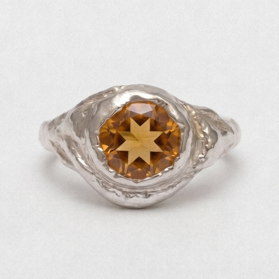 Silver ring with a star-shaped gemstone on a white background