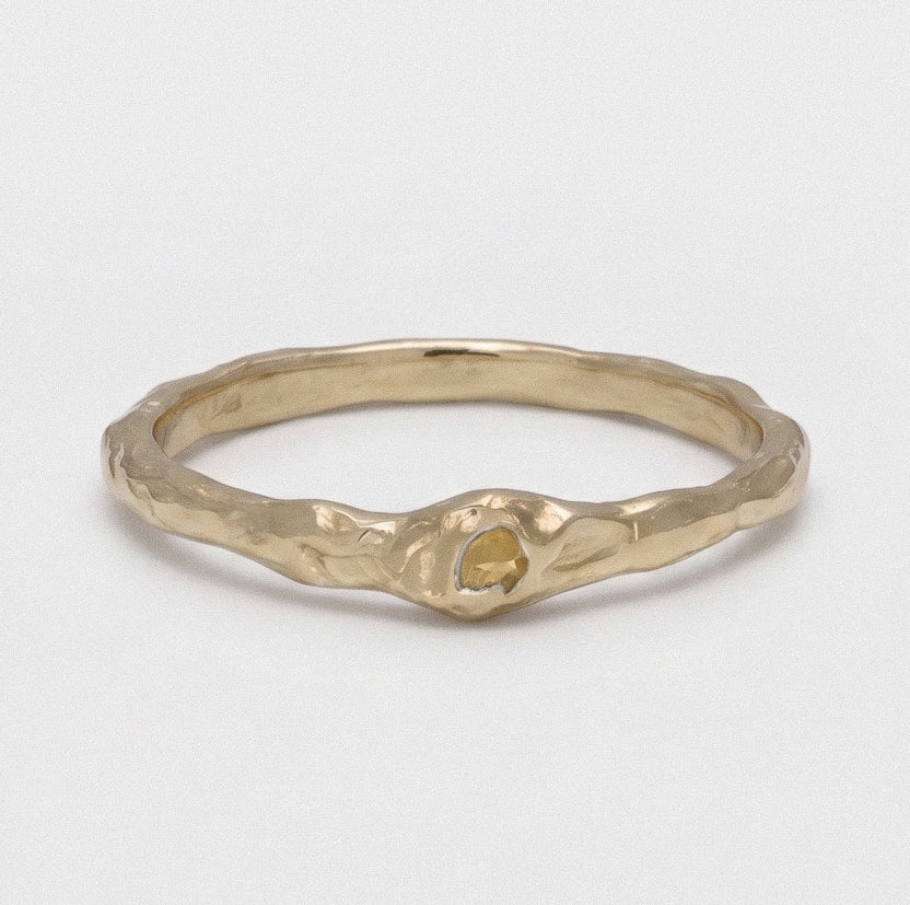Gold ring with a textured design on a light gray background