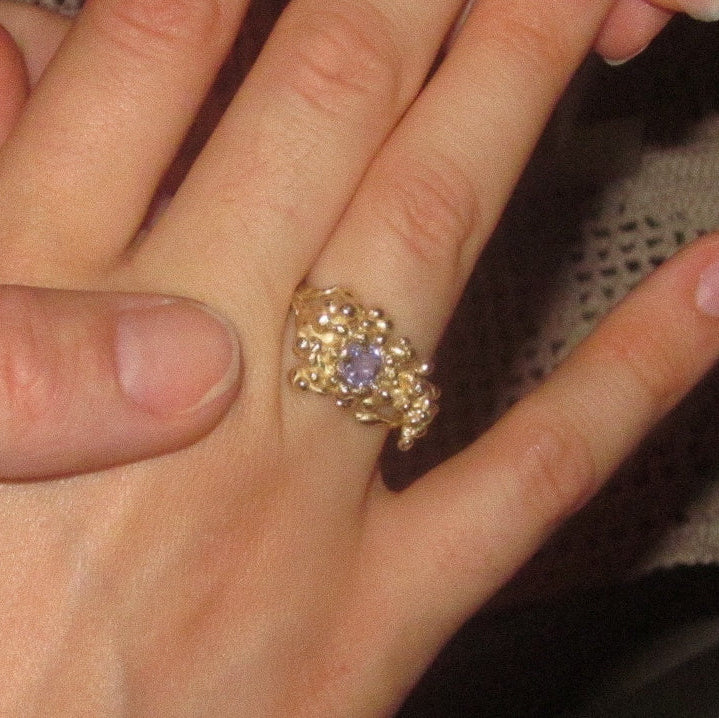Gold ring with a purple gemstone on a hand